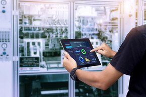 Intelligentes Branchensteuerungskonzept. Hände, die Tablet auf unscharfer Automatisierungsmaschine als Hintergrund halten. | © panuwat - AdobeStock
