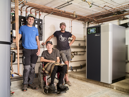Familie Metzler und Norbert lächeln in die Kamera im Keller bei der eingebauten bösch Heizung | © Walter Bösch GmbH & Co KG