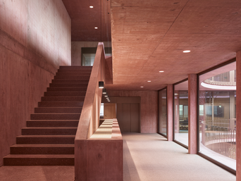 Innovativ gestaltete Büroflächen in der Firmenzentrale von Jäger Bau bieten 140 moderne Arbeitsplätze, die durch fortschrittliche Haustechnik und nachhaltige Materialien wie Holz und rot gefärbten Beton geprägt sind. | © Adolf Bereuter