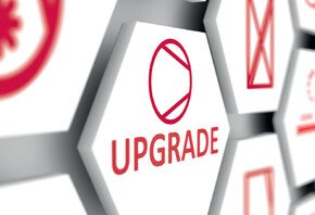Nahaufnahme von einem Button in einer sechseck Form. Darin steht in roter Schrift "Upgrade". 